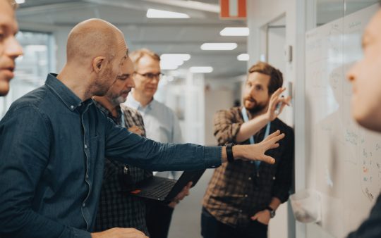 People talking next to a white board