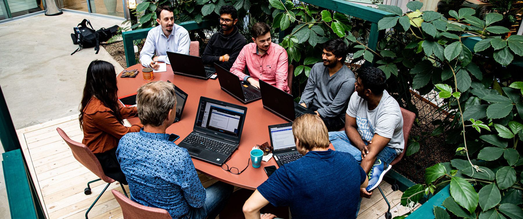 A group of people sitting at a table with laptops talking