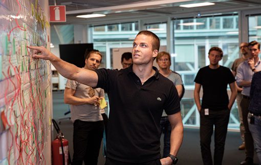 Person pointing at a white board with group of people behind