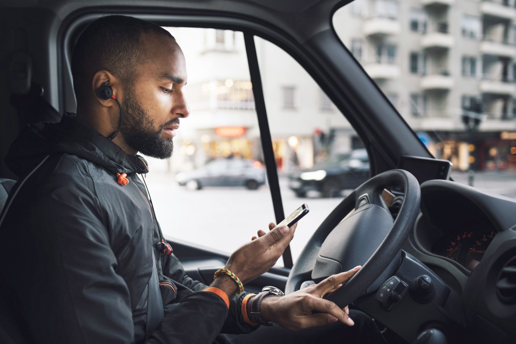 Driver in truck on city street looking at phone