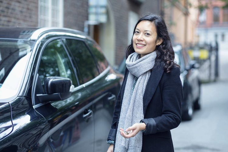 Happy person beside a parked car on street