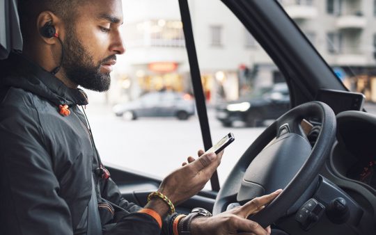 Driver in truck on city street looking at phone