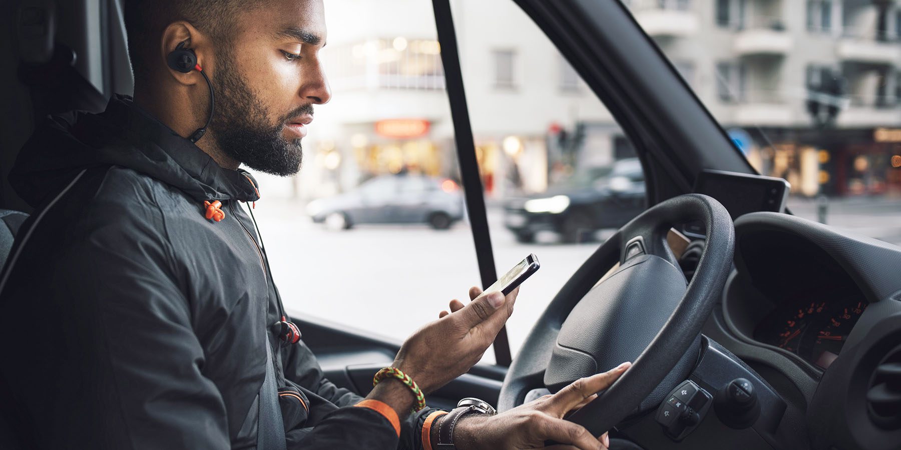 Driver in truck on city street looking at phone