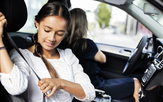 Person putting on seatbelt in car