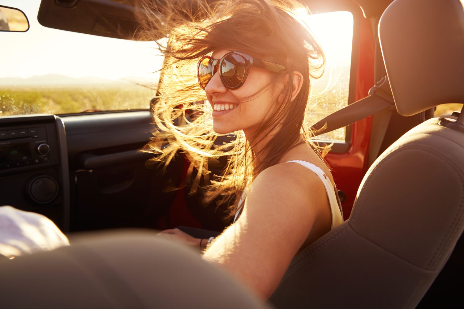 Person sitting in car with sunglasses on a sunny day