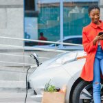 Person standing next to car looking at their phone