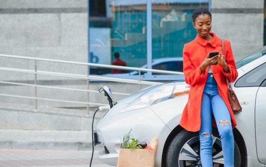 Person standing next to car looking at their phone