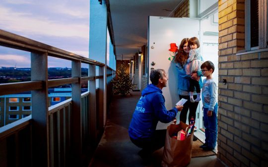 Man giving out gifts to kids apartment house view