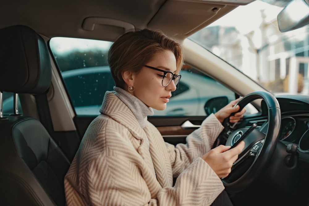 a woman looking at her phone while sitting in a car