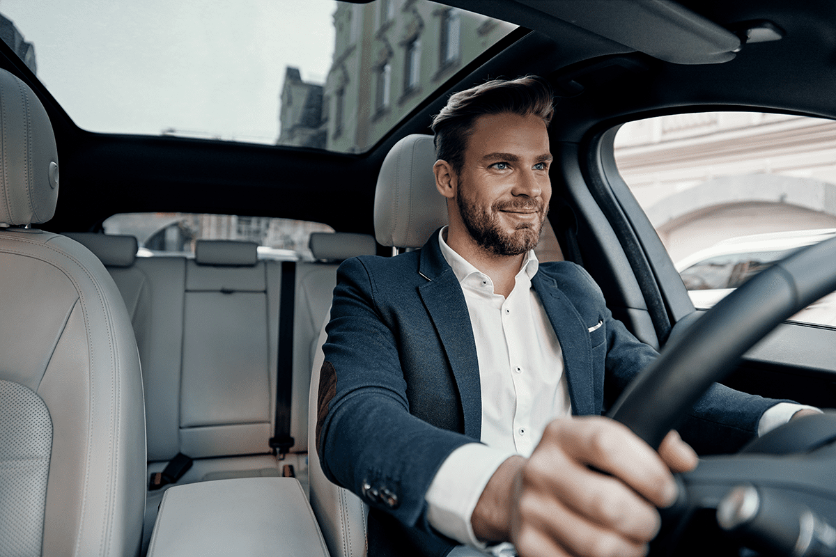 a smiling man driving a car