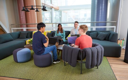 a group of people talking to each other in an office