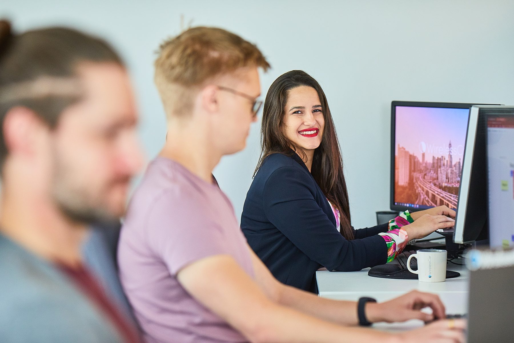 a happy woman seated in front of computer screens