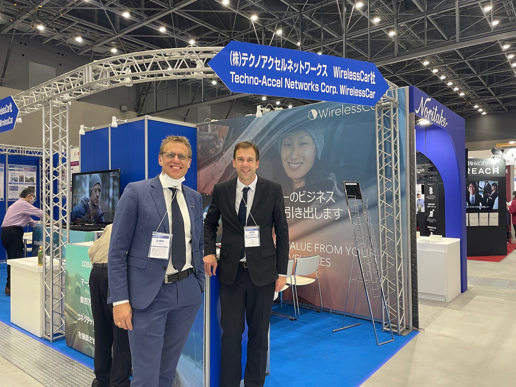 WirelessCar's CEO and his colleague smiling in front of an event booth