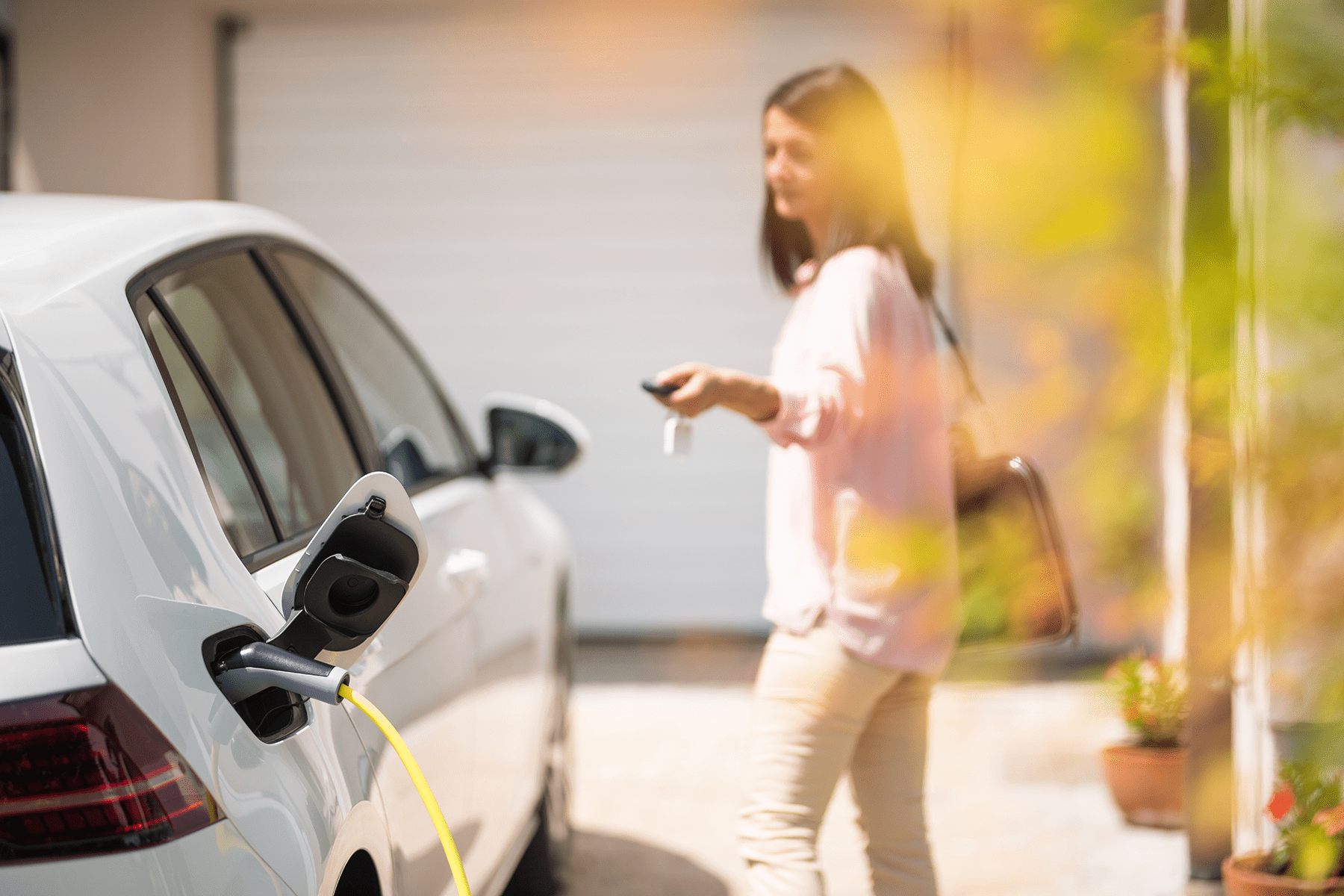 a woman walking away from an electric car, locking it while it's charging