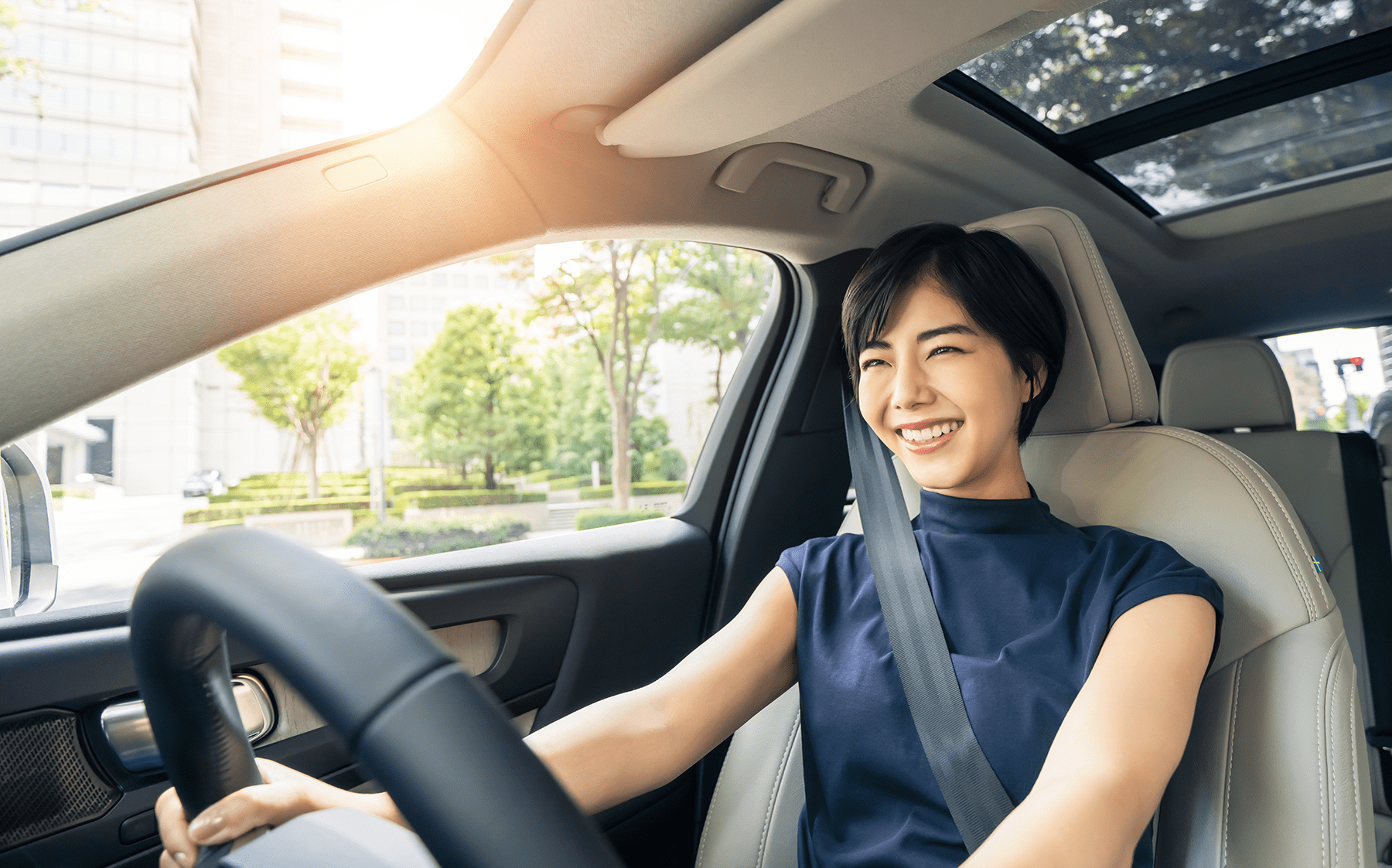 a smiling woman driving a car