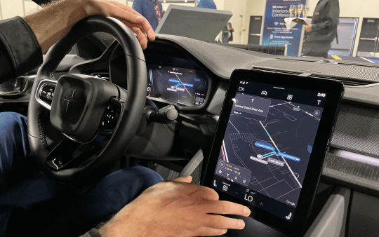 a man sitting inside a modern car and displaying a demo