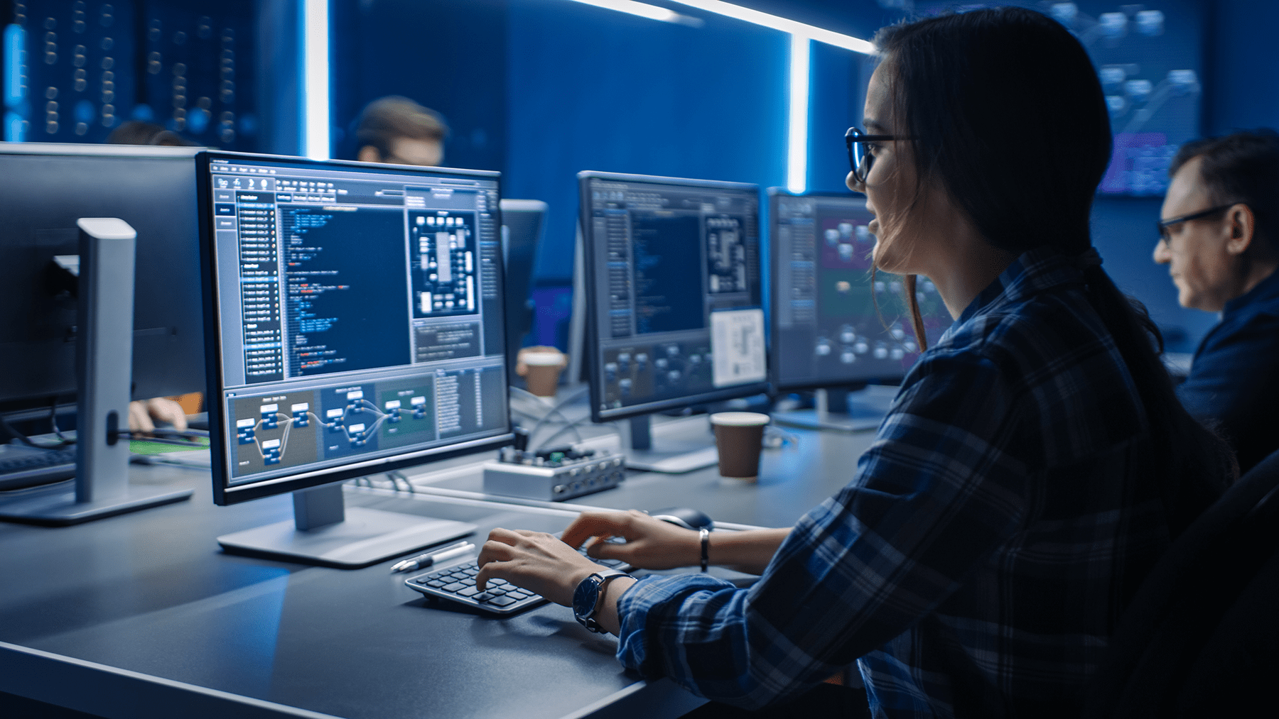 Female IT programer working on desktop computer in data center system control room